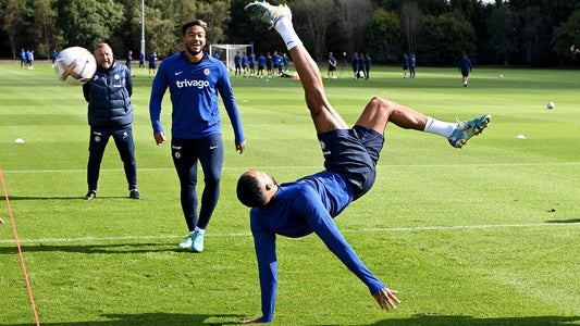 Joueur de Chelsea effectuant un geste acrobatique à l'entraînement ReecebJames en arrière plan avec un coach