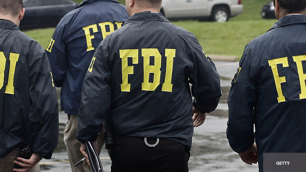 4 agent avec des vestes sombres ou sur le dos il est écrit en gros FBI en jaune 